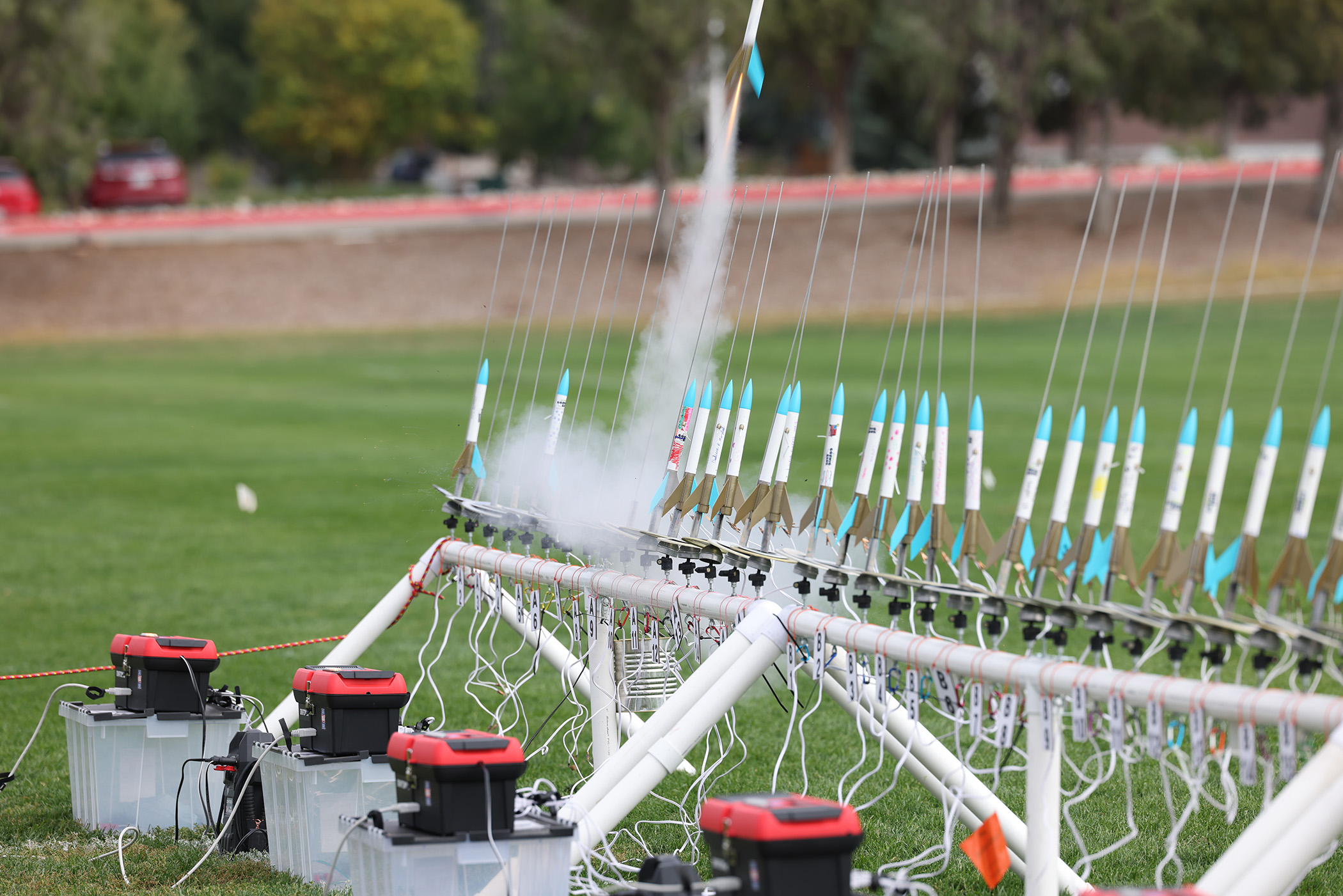 A model rocket lifts off while others await coundown and launch.