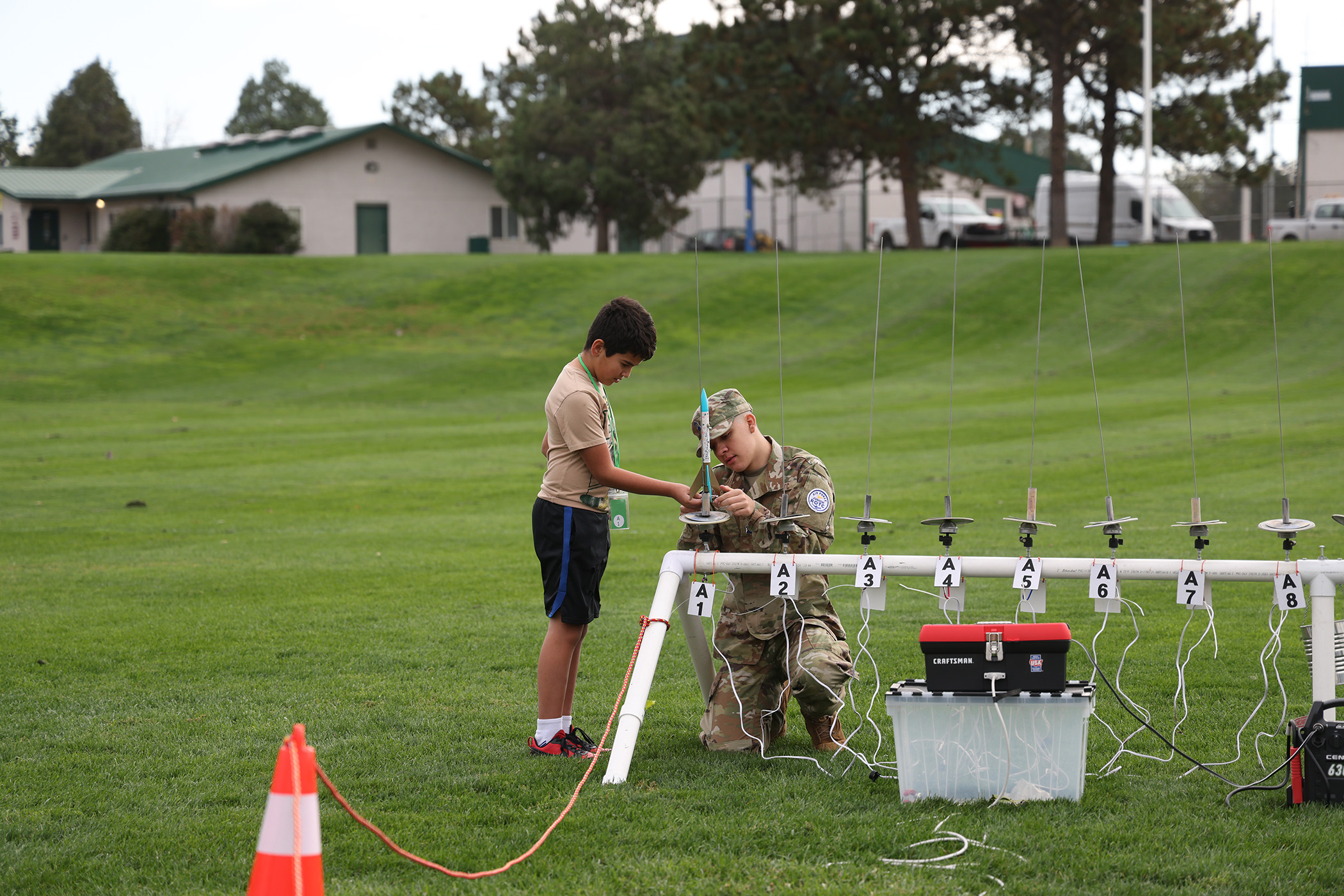 A soldier helps a student prepare his model rocket for launch.